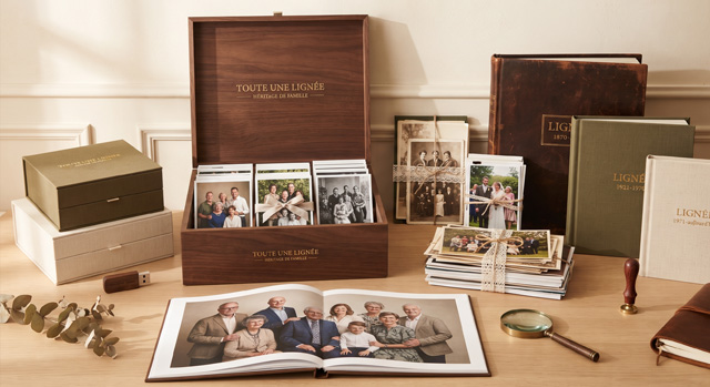 Un grand coffret ouvert, ses tirages classés en trois compartiments, entouré d’albums reliés, de liasses de photos et d’un album ouvert sur un portrait de famille.